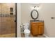 Bathroom featuring walk in shower, neutral tiles, and round mirror above the sink at 2832 Danbury Ave, Highlands Ranch, CO 80126