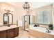 Relaxing bathroom features a soaking tub, glass shower, and elegant chandelier at 15496 W 66Th Dr # G, Arvada, CO 80007