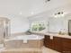 A primary bath with a tub, walk-in shower, natural light and dark wood cabinets creates a spa-like experience at 13971 Star Creek Dr, Broomfield, CO 80023