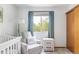 Serene Bedroom showcasing a white crib, comfortable chair, and soft textures, bathed in natural light at 4619 S Tabor Way, Morrison, CO 80465