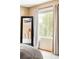 Comfortable main bedroom featuring a window with natural light, a full-length mirror, and neutral decor at 4619 S Tabor Way, Morrison, CO 80465