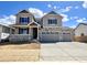 Two-story home featuring a two-car garage, stone accents, gray siding and shutters, and a cozy front porch at 25214 E Warren Pl, Aurora, CO 80018