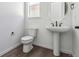 Bright powder room with white pedestal sink, modern fixtures, and wood-look flooring at 25214 E Warren Pl, Aurora, CO 80018