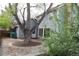 Backyard with a mature tree, a circular patio, and a blue home with a brick chimney at 12381 E Vassar Dr, Aurora, CO 80014