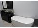 Bathroom with vessel sinks, glass countertop, and luxurious white soaking tub at 12381 E Vassar Dr, Aurora, CO 80014