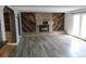 Bright living room with a brick fireplace, wood paneled wall, and gray wood floor at 12381 E Vassar Dr, Aurora, CO 80014