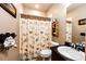 Charming bathroom with decorative shower curtain, wooden accents, and functional shelving for storage at 56607 E 23Rd Ave, Strasburg, CO 80136