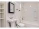 Bright bathroom featuring white sink, toilet, and shower/tub combo with a black framed mirror at 19033 E 22Nd Cir, Aurora, CO 80011