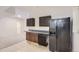 Basement kitchenette featuring dark cabinets and appliances, tile flooring and countertops at 19033 E 22Nd Cir, Aurora, CO 80011