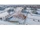 Aerial view of a house with a snowy horse pasture and surrounding houses at 16122 Emporia Way, Brighton, CO 80602