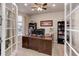 Inviting home office with glass French doors, built in bookcase, and large wooden desk at 2454 Ambience Ln, Castle Rock, CO 80109