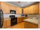Well-lit kitchen with light wood cabinets, black appliances, and wood flooring at 3454 Cascina Pl # D, Highlands Ranch, CO 80126