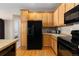 Bright kitchen with light wood cabinets, tile countertops and black appliances at 3454 Cascina Pl # D, Highlands Ranch, CO 80126