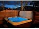 Outdoor hot tub with glowing blue water, surrounded by a wooden fence and trees at night at 1312 Pine View Rd, Golden, CO 80403