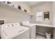 Functional laundry room featuring a washer, dryer, storage shelf, and window for natural light at 1312 Pine View Rd, Golden, CO 80403