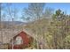 Scenic view from the deck featuring a red home and the mountains, framed by mature trees at 1312 Pine View Rd, Golden, CO 80403