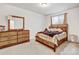 Comfortable bedroom with a wooden frame bed, carpeted floors, and wooden dresser with mirror at 17276 E 103Rd Ave, Commerce City, CO 80022