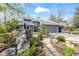 A beautifully landscaped property featuring a unique rock feature, lush plants, and a gray home at 7126 Cedarwood Cir, Boulder, CO 80301