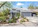 Inviting gray home featuring a stone waterfall feature, lush landscaping, and an attached two-car garage at 7126 Cedarwood Cir, Boulder, CO 80301
