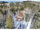 Aerial view of a wooden house nestled in a snowy forest at 11498 Pauls Ln, Conifer, CO 80433