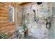 Spa-like shower with glass enclosure and stone tile at 11498 Pauls Ln, Conifer, CO 80433