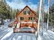 Charming log home featuring a spacious wooden deck and surrounded by mature trees in a serene, snow-covered setting at 11498 Pauls Ln, Conifer, CO 80433