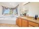 Bathroom featuring a garden tub, large window, and wood-style vanity at 8743 Fairview Oaks Ln, Lone Tree, CO 80124