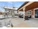 Covered back patio featuring outdoor seating and a stone fireplace in a serene, snow-covered setting at 1128 Starglow Pl, Highlands Ranch, CO 80126