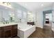 Bathroom with double vanity, oval soaking tub, and view into bedroom at 1128 Starglow Pl, Highlands Ranch, CO 80126