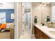 Bathroom with double vanity, white countertop, wooden cabinets, and a view into an adjacent bedroom at 1128 Starglow Pl, Highlands Ranch, CO 80126