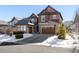 Two-story home with stone and shingle accents, attached garage, basketball hoop, and snow-covered landscaping at 1128 Starglow Pl, Highlands Ranch, CO 80126