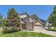View of a two-story home featuring a two-car garage, well-maintained lawn, and mature landscaping at 11803 E 114Th Pl, Commerce City, CO 80640