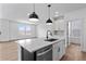 Kitchen island with waterfall countertops, stainless dishwasher, gooseneck faucet and black pendant lighting at 223 Washington St, Erie, CO 80516