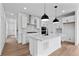 Modern kitchen boasts white cabinets, stainless steel appliances, large island with marble countertops and pendant lighting at 223 Washington St, Erie, CO 80516