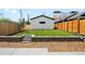 Well-manicured backyard featuring a modern garage with ample green space and a stone retaining wall at 4131 Osage St, Denver, CO 80211
