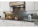 Detailed kitchen with sleek black cooktop, geometric backsplash, and stylish white cabinetry at 942 S County Road 129 Rd, Bennett, CO 80102