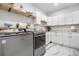 Bright laundry room featuring white cabinets, open shelving, marble countertops, and modern washer and dryer at 942 S County Road 129 Rd, Bennett, CO 80102
