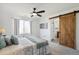 Bedroom featuring a ceiling fan and barn door leading to ensuite bath at 14881 E 117Th Ave, Commerce City, CO 80603