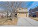 Two-story home showcasing a wide driveway and attached garage with brick accents and mature trees at 14881 E 117Th Ave, Commerce City, CO 80603