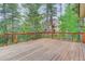 Spacious deck with wood floors and black metal railing, surrounded by tall trees at 9209 William Cody Dr, Evergreen, CO 80439