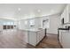 Open kitchen with sleek island, white cabinets, modern appliances, and hardwood floors at 19040 E 96Th Pl, Commerce City, CO 80022