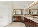 Elegant bathroom features dark wood cabinetry, granite countertops, dual mirrors with decorative lighting, and tile floors at 9556 Kemper Dr, Lone Tree, CO 80124
