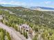 A beautiful mountain home with wood siding is nestled among the trees with snow capped mountains in the distance at 11766 Coal Creek Heights Dr, Golden, CO 80403