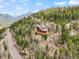 A beautiful mountain home with wood siding and a large deck is nestled among the trees on a hillside at 11766 Coal Creek Heights Dr, Golden, CO 80403