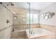 Bright bathroom with a tiled shower, soaking tub, decorative mirrors, and a window at 5265 S Cathay Way, Centennial, CO 80015