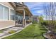 Well-manicured back yard with artificial turf, a covered porch, and mature trees at 3214 Heron Lakes Pkwy, Berthoud, CO 80513