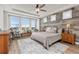 Spacious primary bedroom with wood-paneled accent wall, large windows, and ceiling fan at 3214 Heron Lakes Pkwy, Berthoud, CO 80513