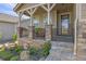 Front porch with stone pillars, metal railing, and flower planters at 3214 Heron Lakes Pkwy, Berthoud, CO 80513