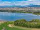 Picturesque lake view showcasing lush greenery, sand traps and a stunning mountain backdrop at 3214 Heron Lakes Pkwy, Berthoud, CO 80513