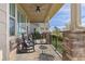 Inviting covered porch with rocking chairs, stone pillars, and outdoor ceiling fan at 3214 Heron Lakes Pkwy, Berthoud, CO 80513